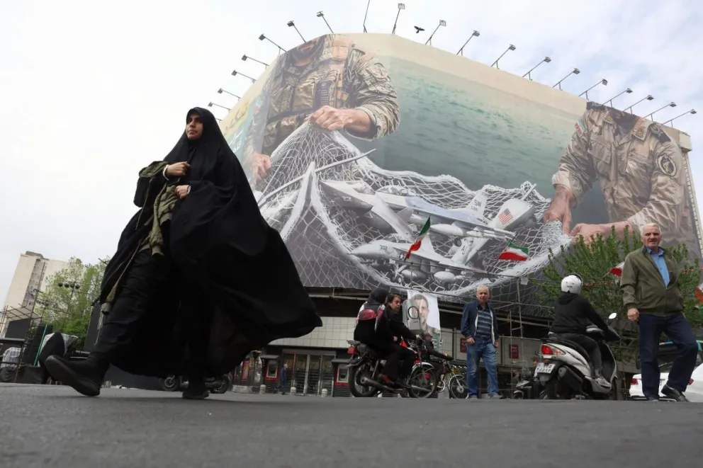 Una mujer camina el pasado domingo 12 de abril en Teherán ante un mural que reza en persa 'El estrecho de Ormuz seguirá cerrado', en la plaza Enghelab de la capital. Foto: EFE