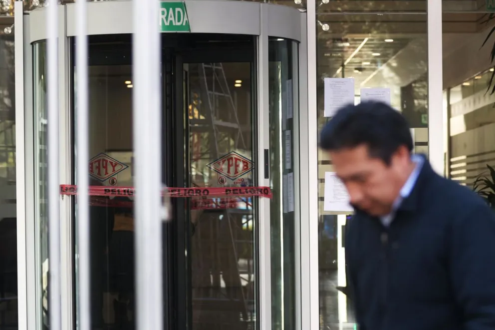 Una persona camina frente a la puerta de acceso al edificio de Yacimientos Petrolíferos Fiscales Bolivianos (YPFB) este viernes, en La Paz (Bolivia). EFE/ Luis Gandarillas
