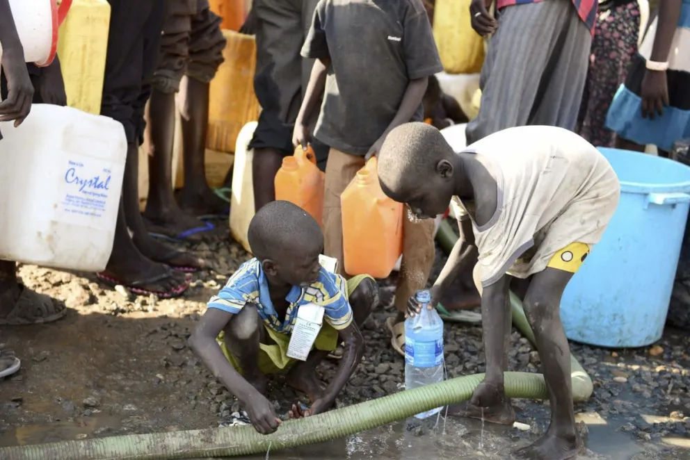 os niños llenan una botella de agua en un área de protección establecida por la misión de las Naciones Unidas en Sudán del Sur (UNMISS) en Juba (Sudán). Foto: EFE
