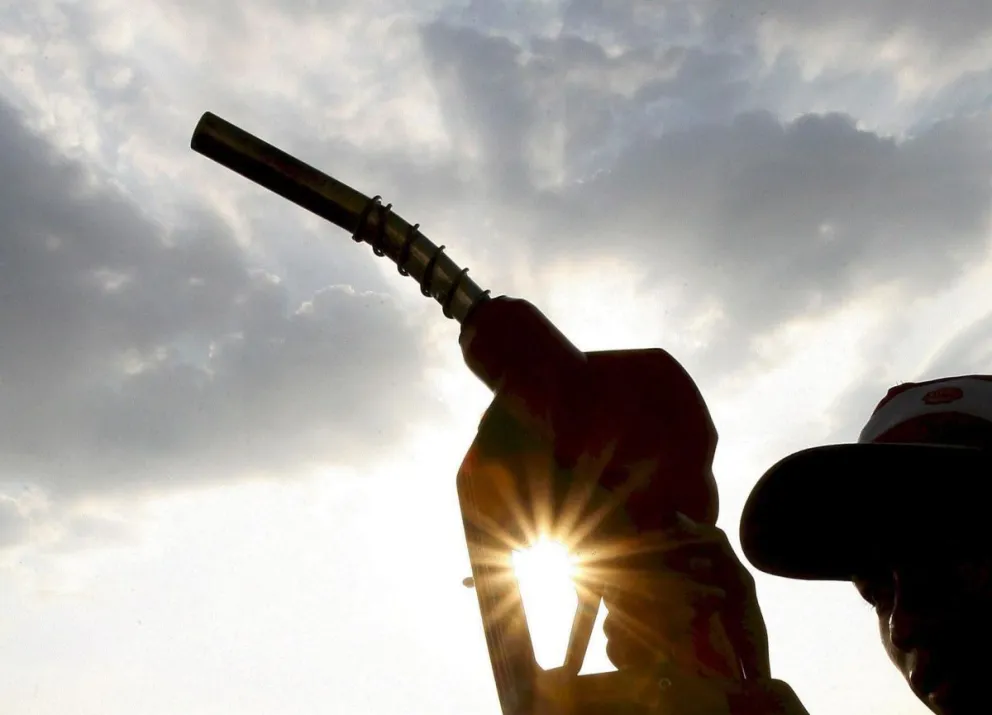 Un hombre con la manguera de un surtidor de una gasolinera. Foto: EFE