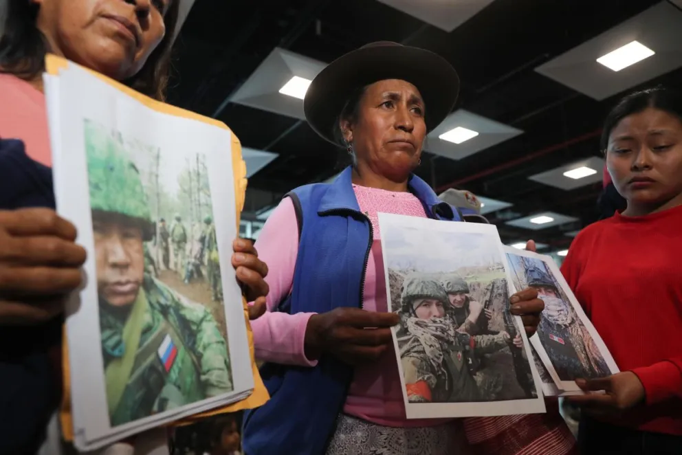 Familiares de peruanos reclutados por Rusia para la guerra contra Ucrania fueron captados este 4 de mayo al sostener fotografías de sus allegados, en el aeropuerto internacional Jorge Chávez, cerca a Lima (Perú). Foto: EFE