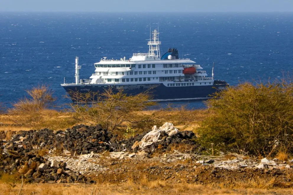 El crucero holandés MV Hondius (atrás), anclado frente a la costa de la ciudad de Praia en la isla de Santiago, Cabo Verde, este lunes 4 de mayo de 2026, después de que tres personas murieran a bordo a causa de un síndrome respiratorio agudo. Foto: EFE 