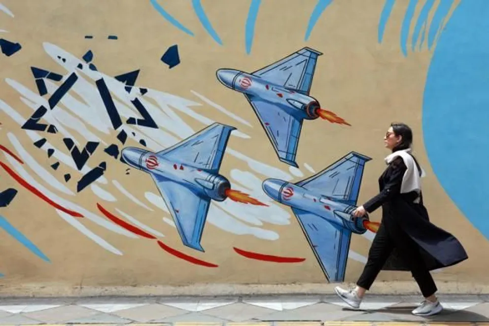 Una iraní camina junto a un mural anti-EE. UU. e Israel en una calle de Teherán. Foto EFE