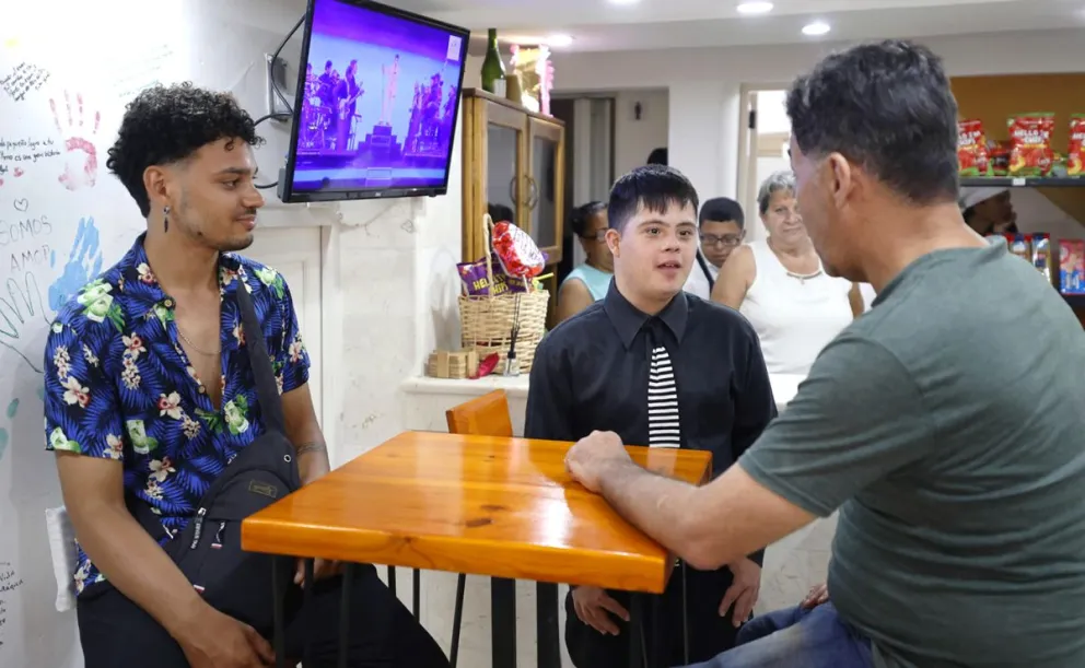 El joven Livan Valle (c), habla con clientes en la cafetería donde trabaja en La Habana (Cuba). Foto: EFE
