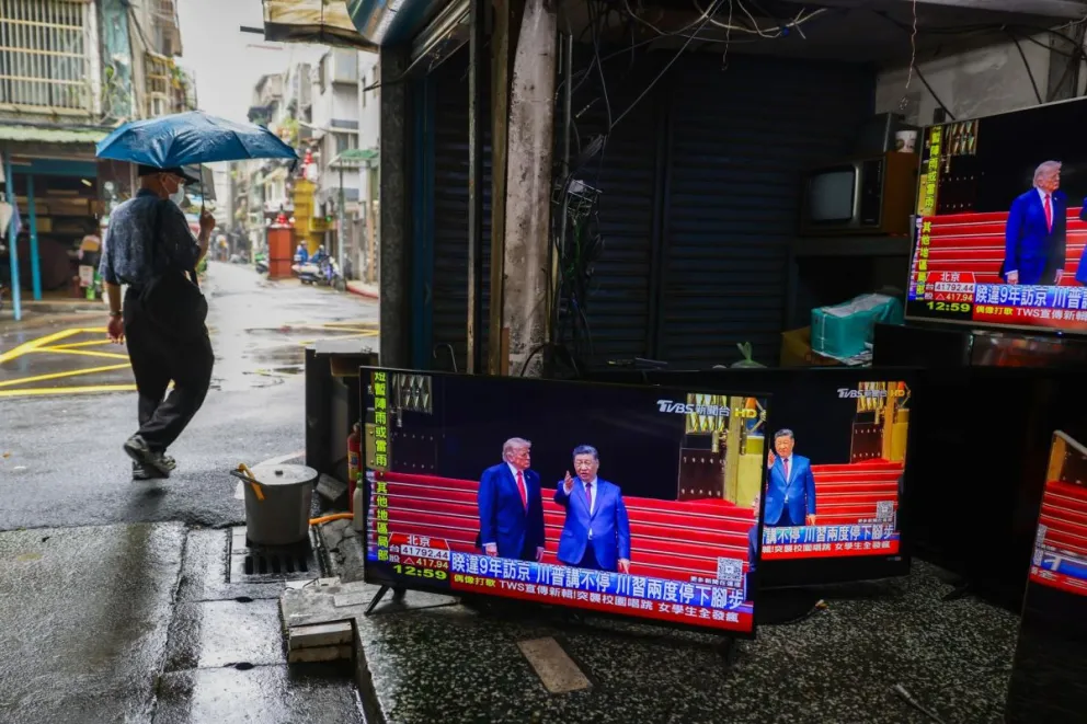 Un peatón pasa junto a una tienda de segunda mano y reparación de televisores, con pantallas que transmiten la reunión en Pekín entre el presidente estadounidense, Donald Trump, y el chino, Xi Jinping, en Taipéi, Taiwán, el 14 de mayo de 2026. Foto: EFE