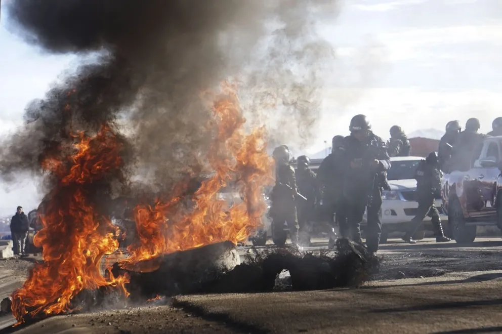 Policías avanzan en medio de llantas quemadas durante el operativo para el corredor humanitario. Foto: APG