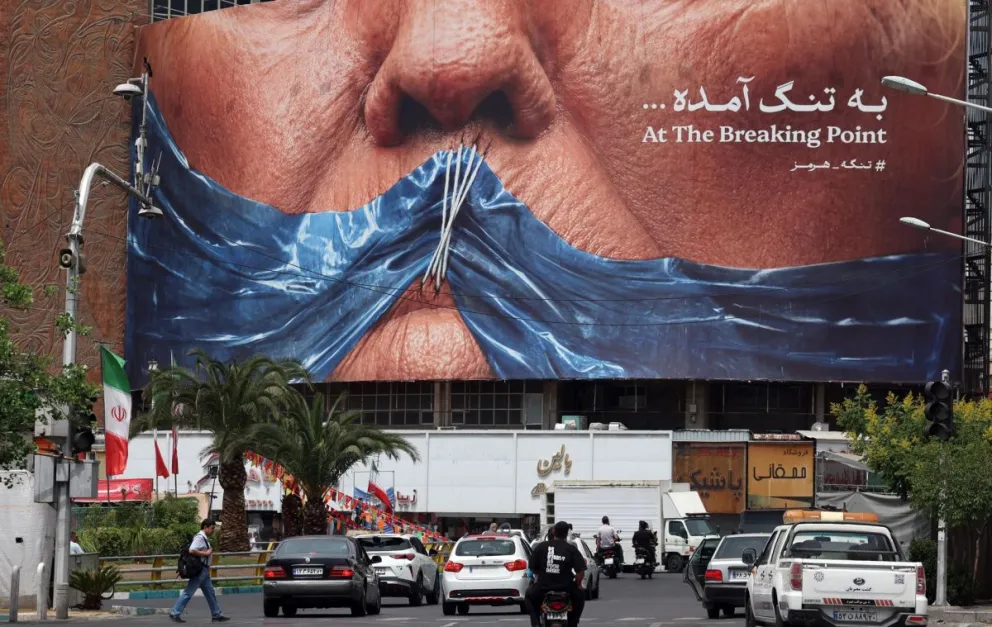 Iraníes conducen frente a un gran cartel antiestadounidense que muestra al presidente estadounidense Donald Trump y el estrecho de Ormuz en la plaza Valiasr en Teherán, Irán, el 28 de mayo de 2026. Foto: EFE 