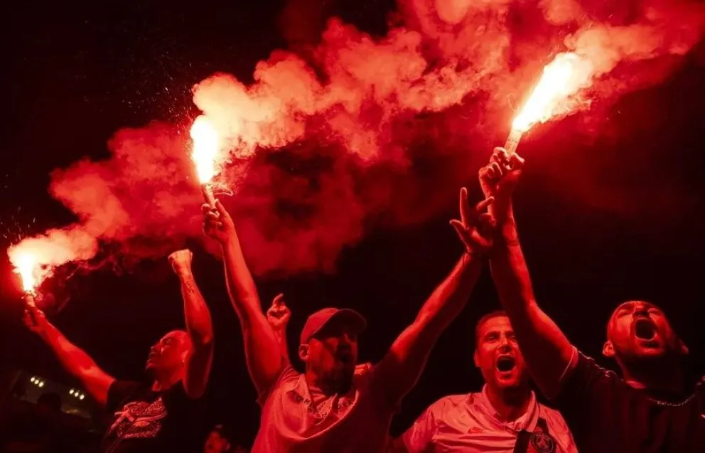 Hinchas del París Saint-Germain celebran con bengalas en la Fan Zone tras la victoria de su equipo sobre el Arsenal. Foto: EFE