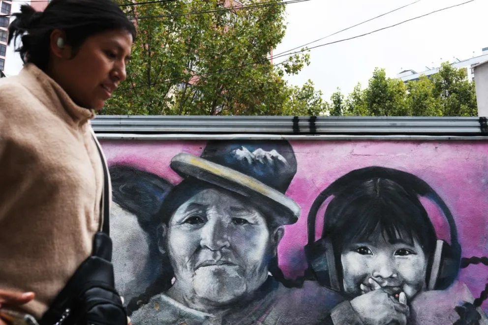 Fotografía de archivo que muestra a una persona caminando frente a un mural con el dibujo de una niña en La Paz (Bolivia). Foto: EFE