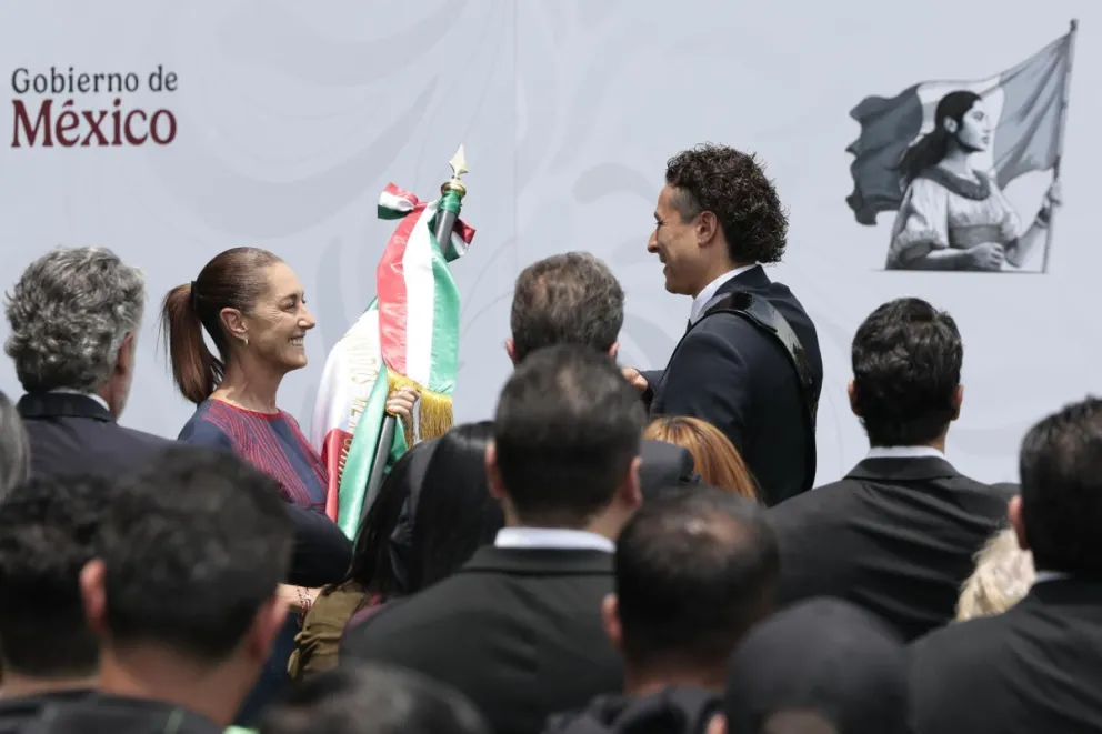 Sheinbaum (izq.), entrega una bandera al arquero Ochoa durante la ceremonia de abanderamiento. Foto: EFE.