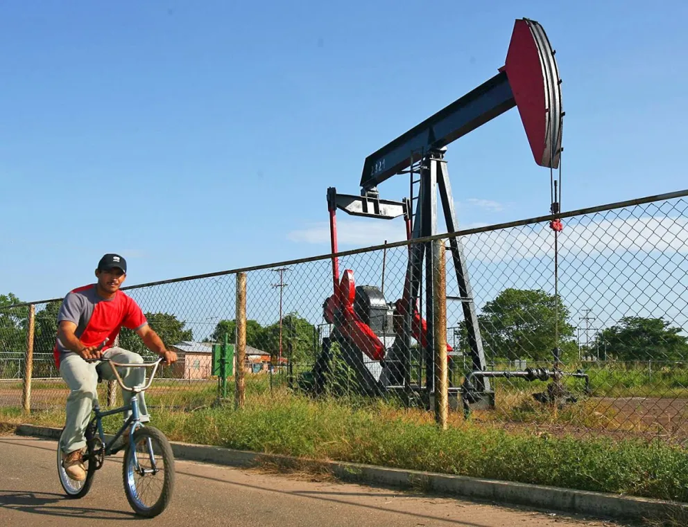 Imagen de archivo de un hombre en bicicleta al pasar cerca de un pozo petrolero en la Costa Oriental del Lago de Maracaibo (Zulia, Venezuela). Foto: EFE