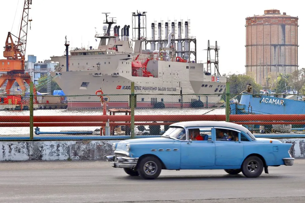 Fotografía de archivo en la que se captó el paso de un automóvil viejo frente a una planta generadora de electricidad en La Habana (Cuba). Foto: EFE