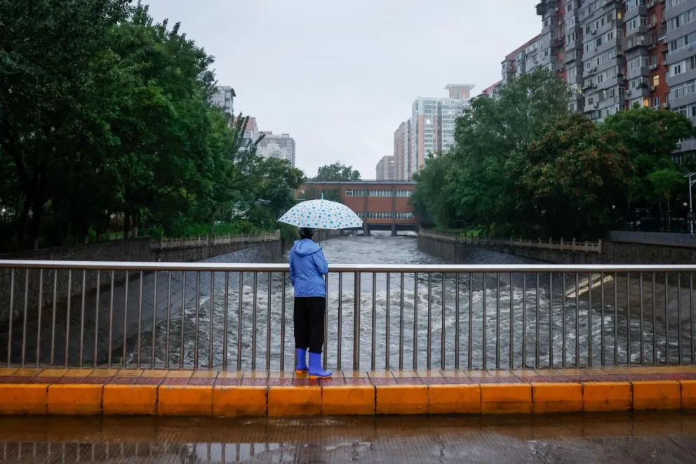 Una mujer observando cómo se vierte agua en un río en Pekín, China., en una fotografía de archivo. Foto: EFE/