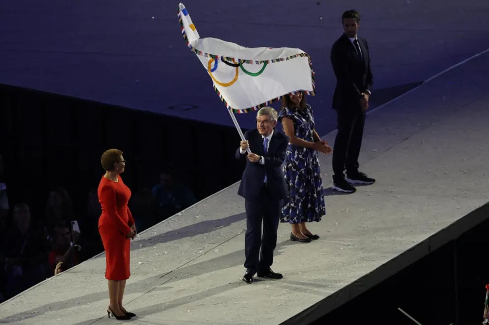 La bandera olímpica en las manos del expresidente del COI, Thomas Bach. Foto: EFE.
