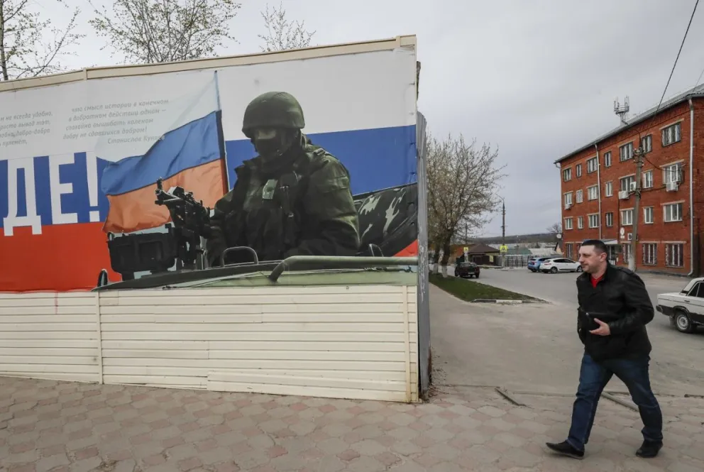 a localidad rusa de Yefremov, en la región de Tula, una de las más afectadas por los ataques de este viernes, en la que un hombre pasa frente a un cartel que representa a un militar ruso armado. Foto: EFE