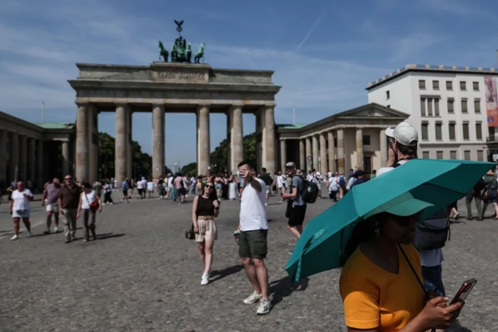 Un turista se protege del sol bajo una sombrilla en frente de la puerta de Brandenburgo in Berlin el 27 de junio de 2026. Foto: EFE