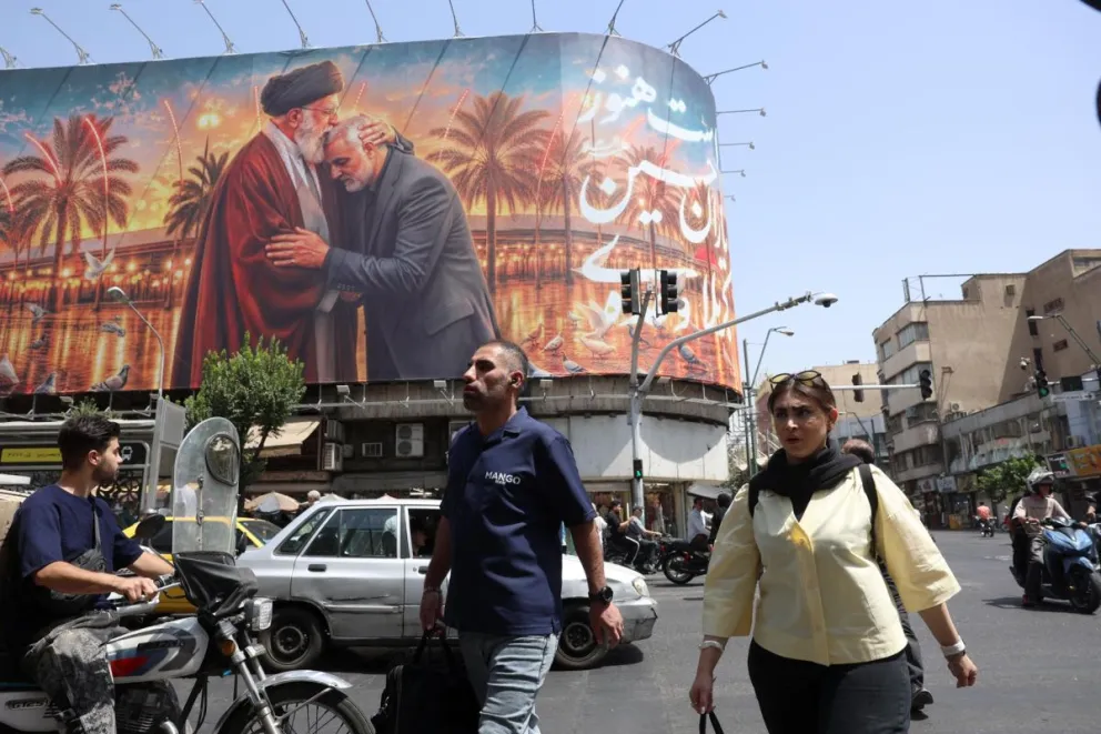 Dos iraníes pasan este lunes 29 junto a un cartel en Teherán que muestra una imagen del fallecido líder supremo de Irán, el ayatolá Ali Khamenei. Foto: EFE 