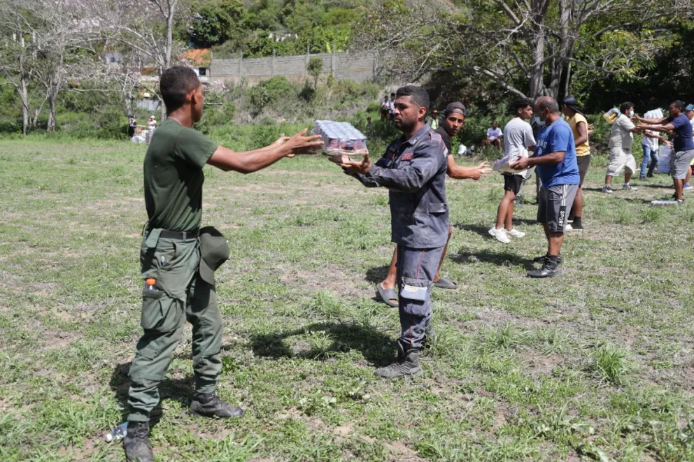 Personas descargan ayudas humanitarias de un helicóptero este lunes, en La Guaira (Venezuela). Foto: EFE/