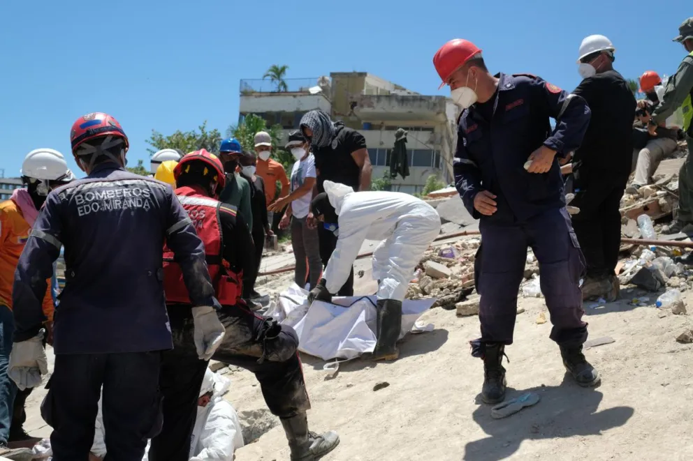 Bomberos y voluntarios rescatan un cuerpo sin vida durante los trabajos de remoción de escombro. Foto: EFE 
