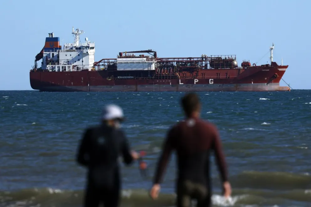 Dos surferos frente a un barco petrolero en Fos-sur-Mer, en el sur de Francia. Foto: EFE