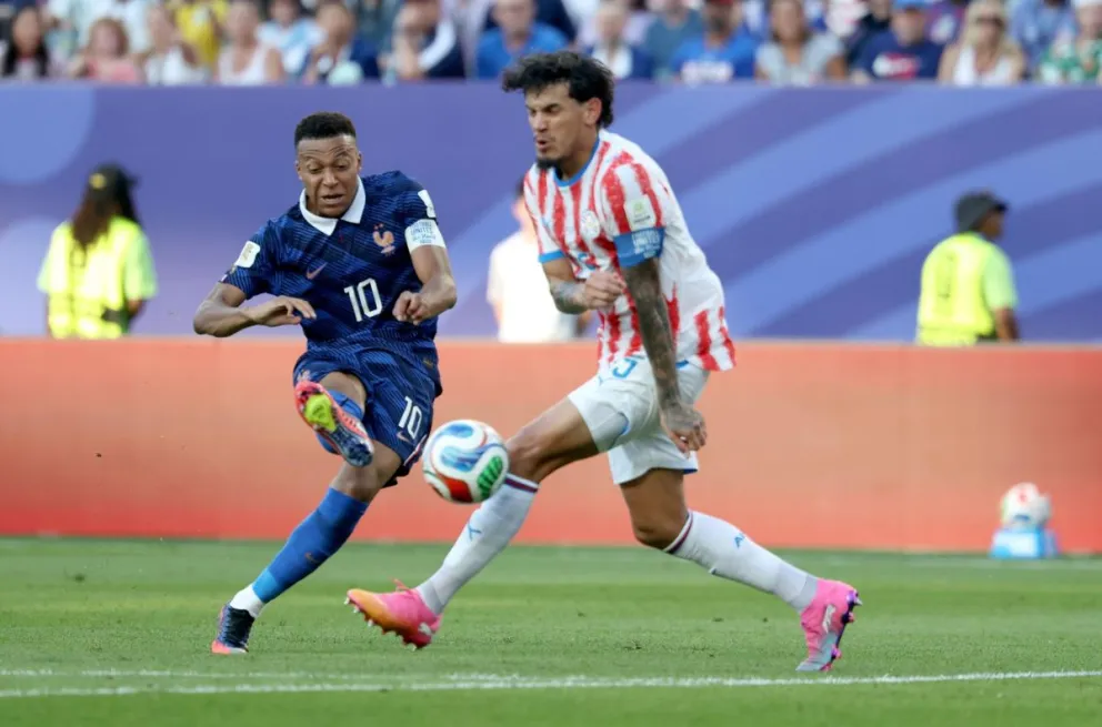 El francés Kylian Mbappé (de azul) patea la pelota durante el partido con Paraguay. Foto: EFE.
