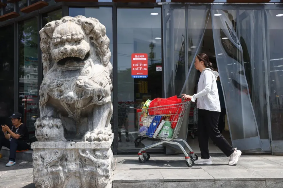 Una mujer camina con un carrito cerca de un supermercado en Pekín. Foto: EFE