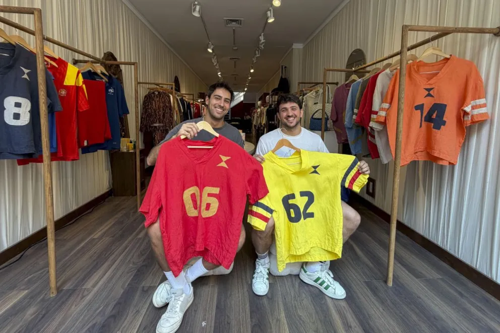 Los dos amigos muestran las camisetas que crearon. Foto: EFE.
