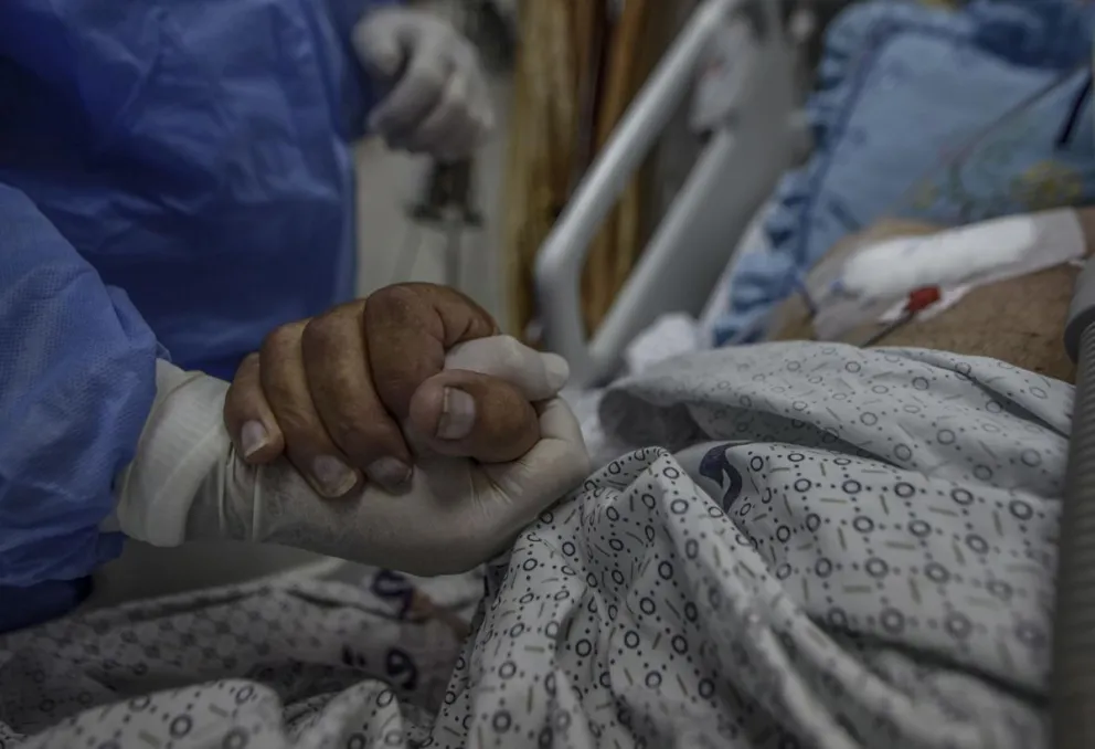 Imagen de archivo de un sanitario que agarra la mano de un paciente del hospital Al-Nasser, al sur de la Franja de Gaza. Foto: EFE