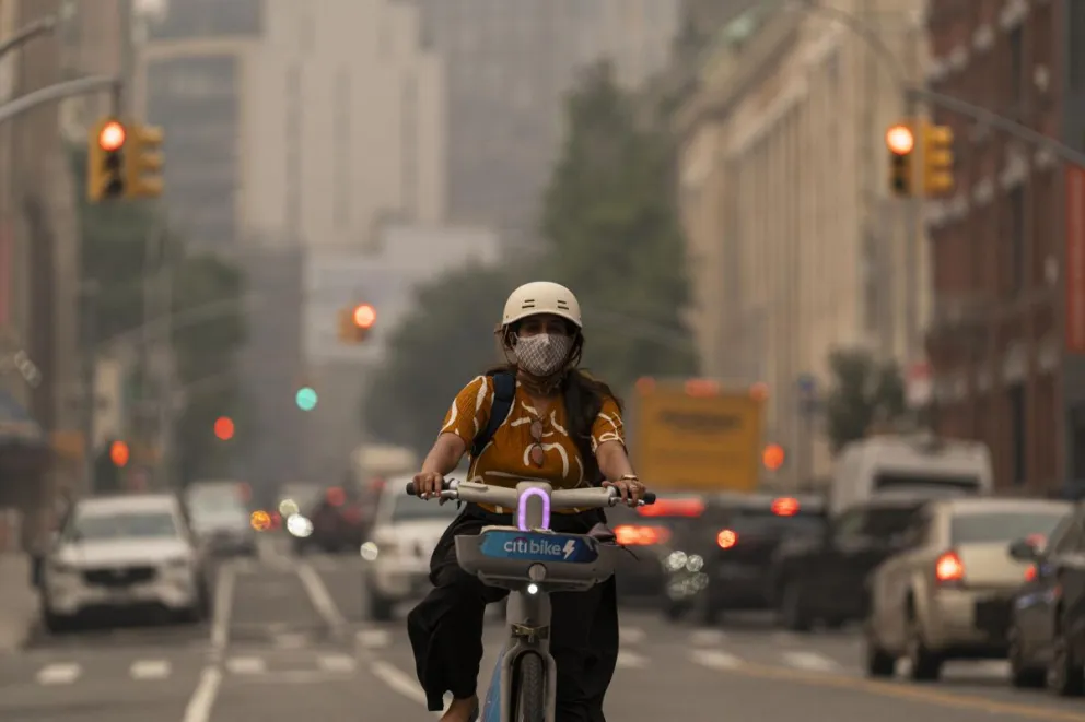 Una joven fue captada este 17 de julio al transitar en bicicleta y con tapabocas, en medio de un densa capa de humo procedente de los incendios forestales en Canadá, en Manhattan (NY, EE.UU.). EFE