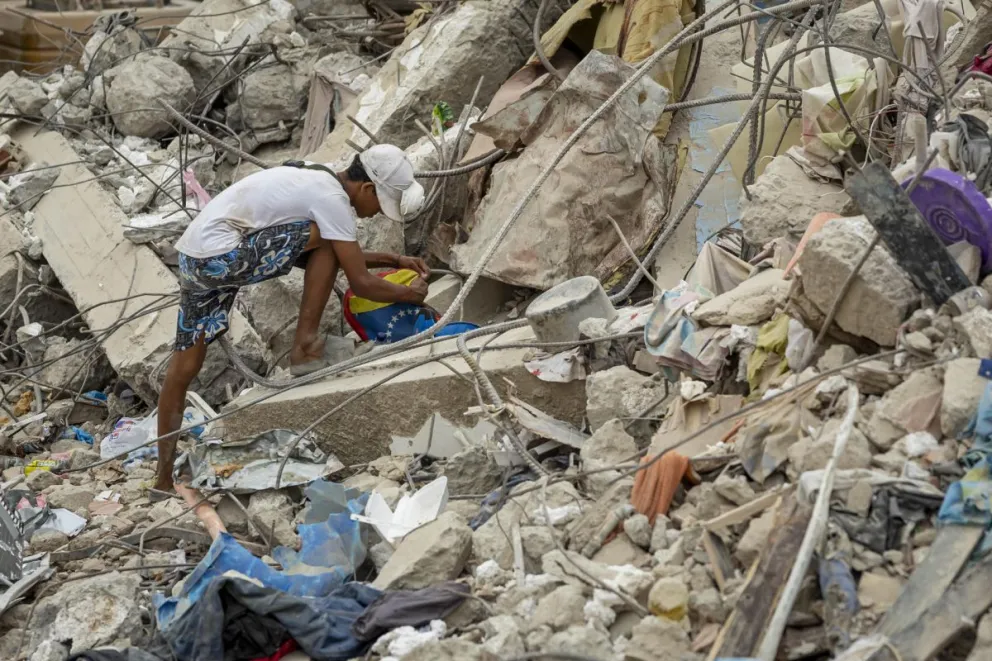 Una persona busca entre los escombros de edificios destruidos por terremotos en Caraballeda (Venezuela). EFE/ Miguel Gutiérrez