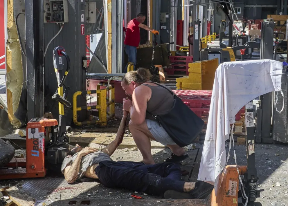Una mujer llora junto al cuerpo de una de las víctimas de un ataque con misiles rusos contra una terminal postal en las afueras de la ciudad ucraniana de Járkov. Foto: EFE