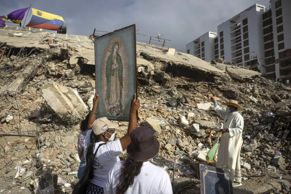 Personas junto al sacerdote Omar Pérez Gabino (d) durante un recorrido para acompañar con oraciones a familiares, voluntarios y rescatistas. Foto: EFE