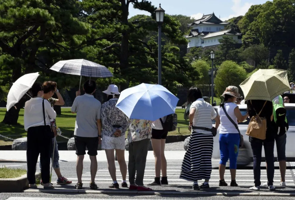 Varias personas se protegen del sol mientras pasean por los jardines del Palacio Imperial en Tokio, Japón, en una fotografía de archivo. Foto: EFE