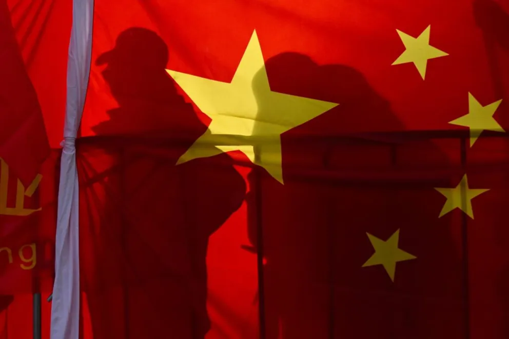 Dos personas tapadas por la bandera de China. Foto: EFE 