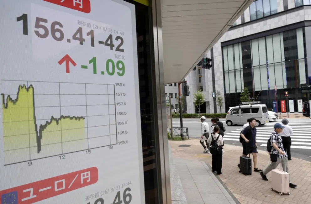 Transeúntes pasan junto a un panel indicador de divisas que muestra el tipo de cambio del dólar estadounidense frente al yen japonés. Foto: EFE 