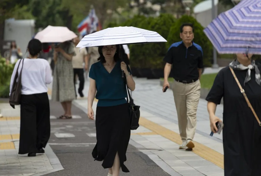 Varias personas caminan con paraguas para resguardarse del calor extremo en la zona de refrigeración de la plaza Cheonggye en Seúl, Corea del Sur. Foto: EFE 