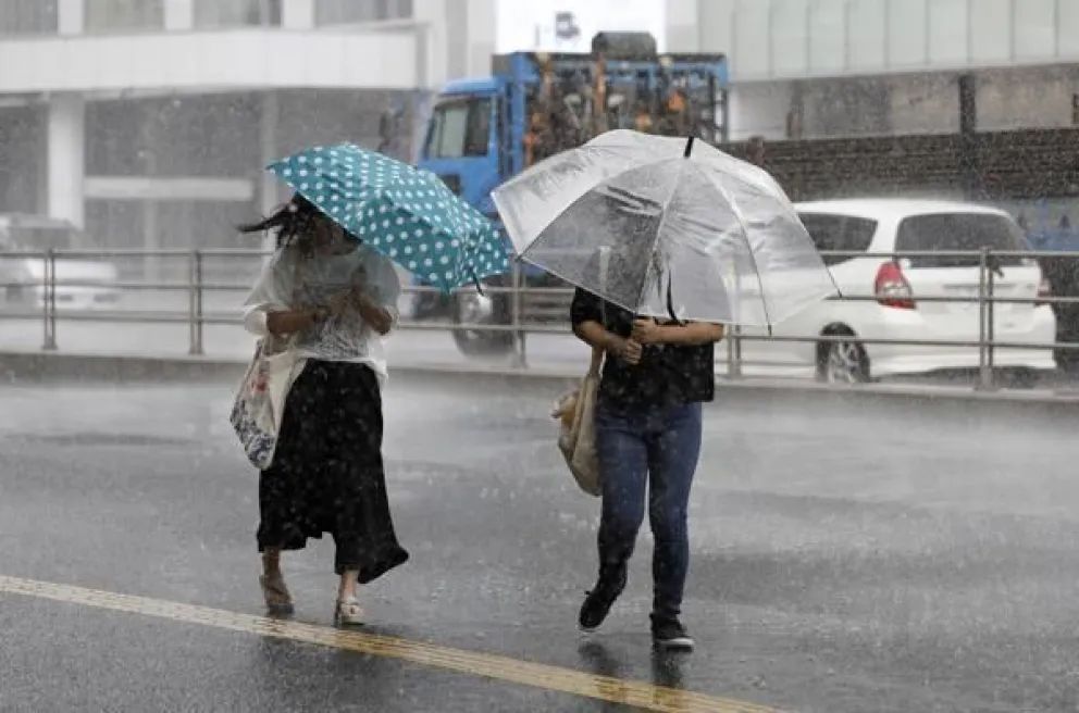 Imagen de archivo de peatones con paraguas luchando contra los fuertes vientos y la lluvia al paso de un tifón por Japón. Foto EFE