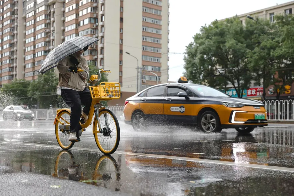 Una persona se moviliza por las calles en medio de una lluvia. Foto: EFE