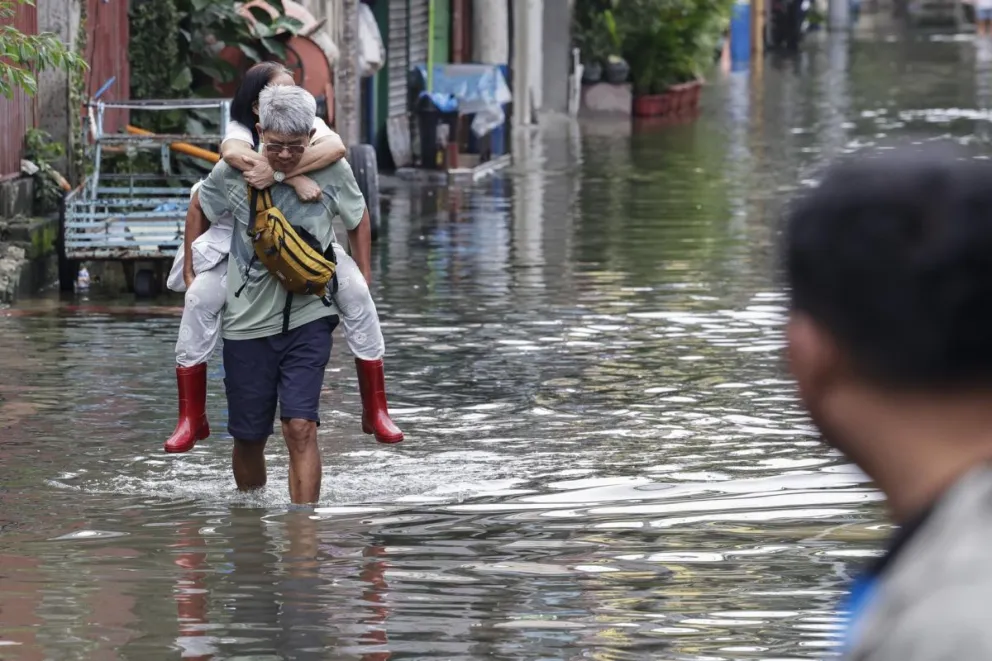 Un hombre carga a su esposa mientras camina entre las aguas de la inundación en la ciudad de Pasig, Manila, Filipinas, el 10 de agosto de 2026. Foto: EFE 