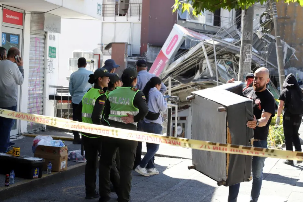 Un hombre recoge pertenencias en una zona custodiada por policías frente a una edificación destruida por un terremoto de magnitud 7,4 este lunes, en Manizales (Colombia). Foto: EFE