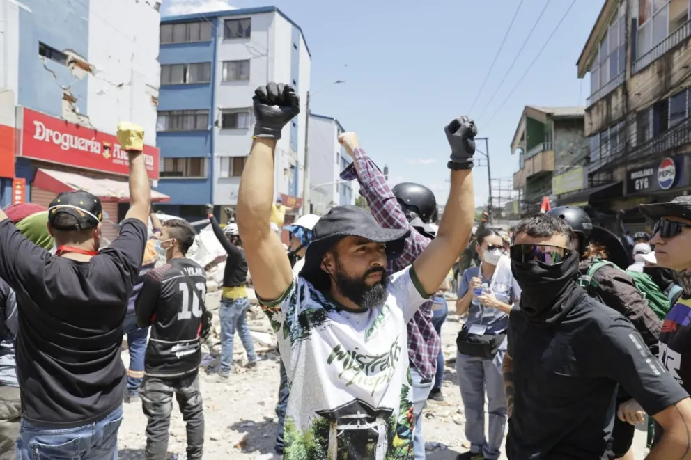 Rescatistas y voluntarios levantan los brazos pidiendo silencio durante una operación de rescate en los escombros de un edificio tras el terremoto de magnitud 7,4 que sacudió la mayor parte de Colombia, este martes en el sector de La Lorena en Pereira. 