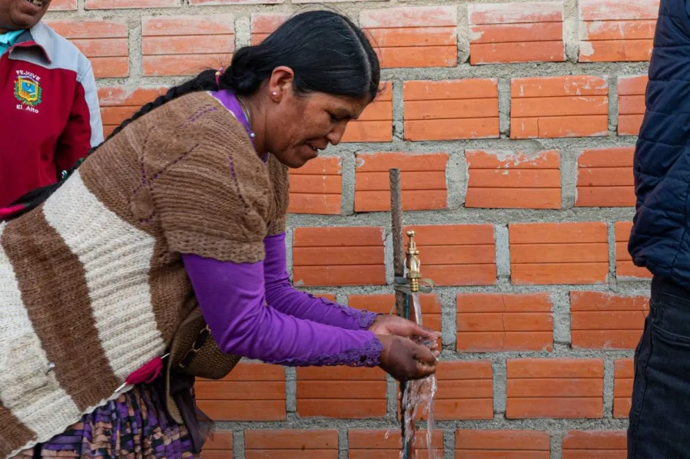 Una mujer recibe agua potable de una pileta. Foto: Epsas