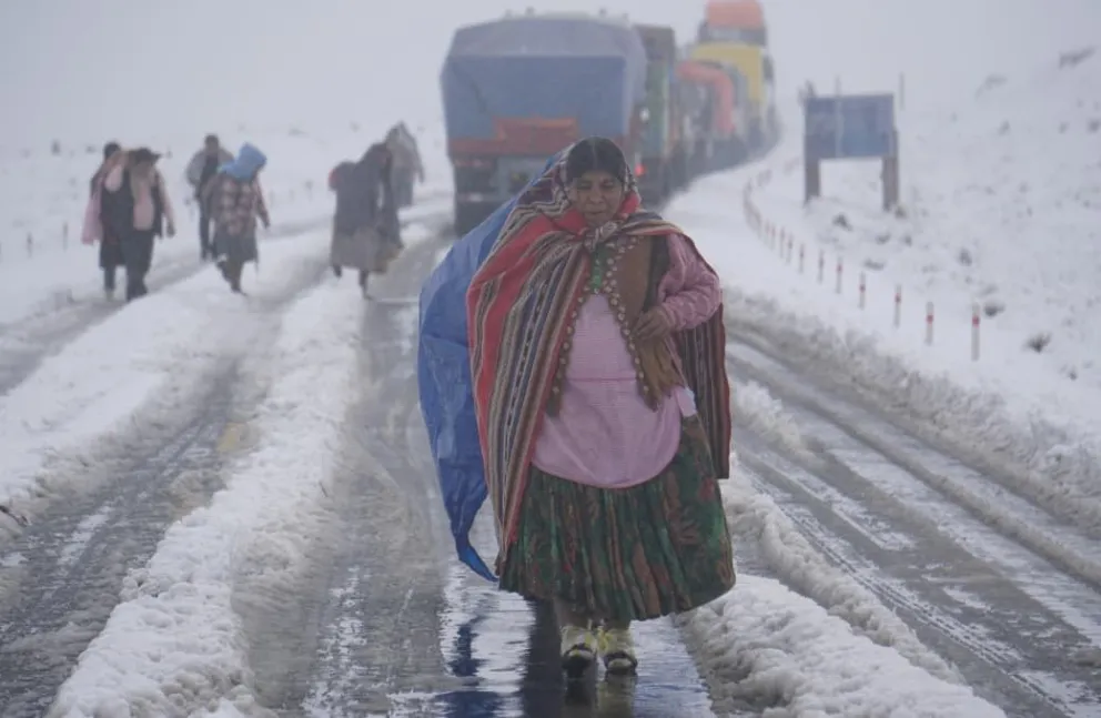 Varios pasajeros intentan llegar a sus destinos caminando, mientras los vehículos no pueden avanzar por la nevada. Foto : APG