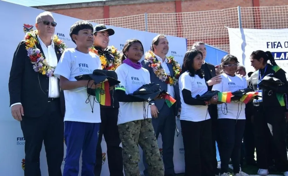 Niños y niñas muestran los zapatos de fútbol que les obsequiaron durante la inauguración de la cancha del programa FIFA Arena. Foto: APG
 