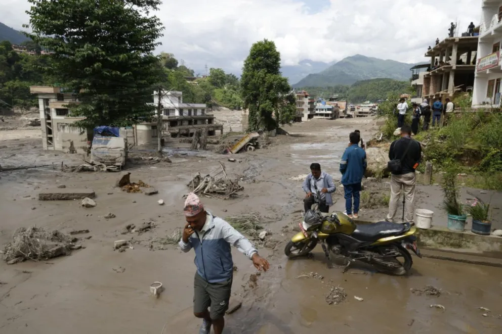 Campesinos avanzan entre el lodo en Trishuli, en el distrito nepalí de Nuwakot, tras una riada repentina. Foto: EFE