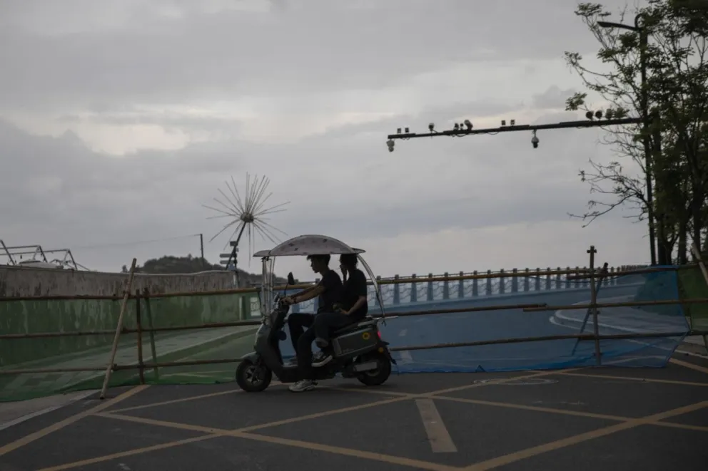 Dos personas circulan en un ciclomotor eléctrico junto a una carretera cortada ante la llegada del tifón Saudel a Yuhuan, en la provincia de Zhejiang (China). Foto: EFE