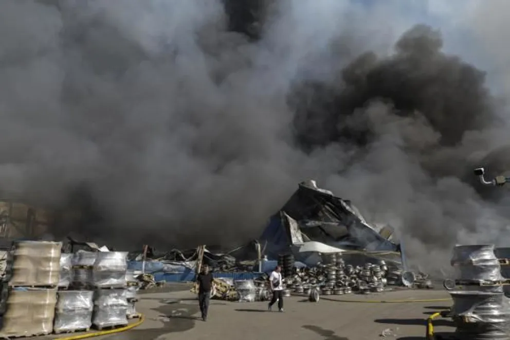 Vecinos caminan en el lugar de un ataque ruso a un almacén de mercancías cerca de Kiev, Ucrania, el 29 de agosto de 2026, en medio de la invasión rusa. Foto EFE