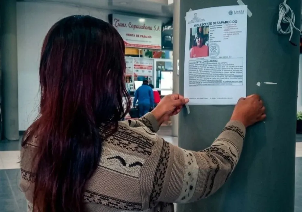 Una mujer coloca un letrero de «búsqueda de persona desaparecida» en la Nueva Terminal de Buses de Tarija. Foto: Yobana Knaudt
