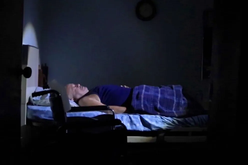 Durmiendo en un colchón junto a la puerta de la entrada de su casa para buscar un soplo de aire en medio del sofocante calor nocturno de Maracaibo. Foto: EFE
