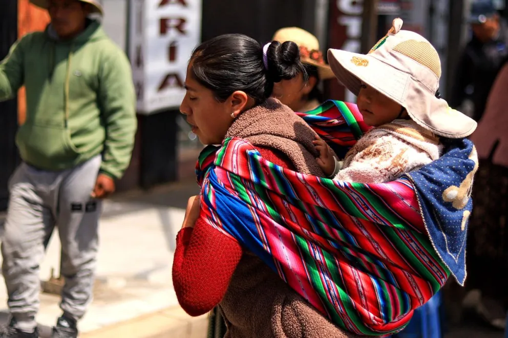 Una mujer aimara camina con una niña en su espalda este miércoles, en El Alto (Bolivia). Foto: EFE